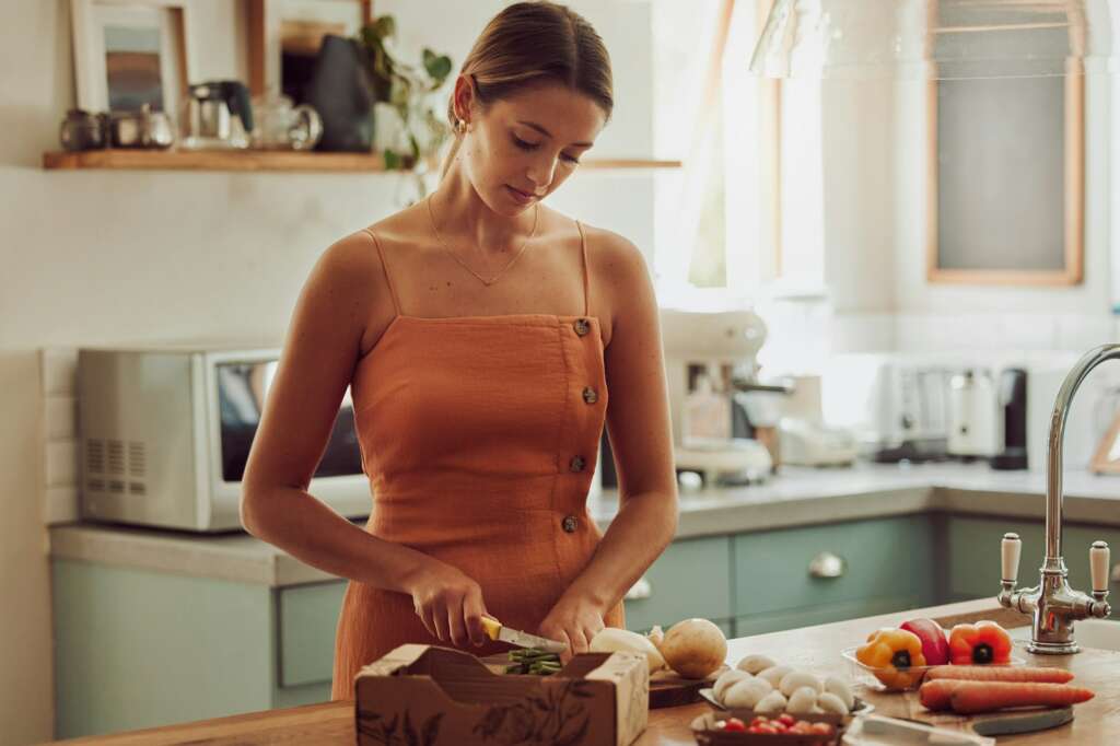 Cooking, healthy and cutting vegetables while a woman prepares an organic, nutritional and vegetari