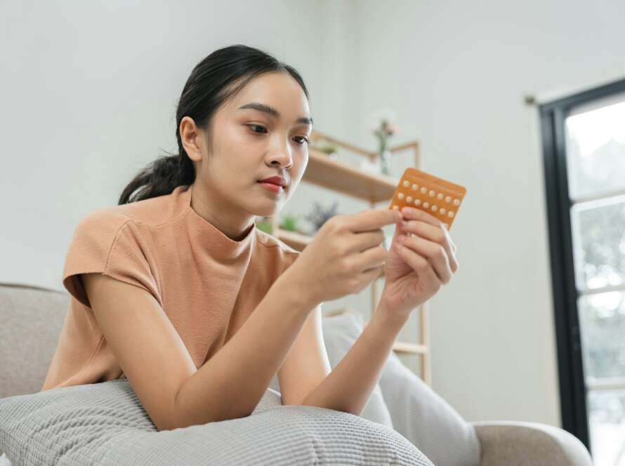 Woman Taking Birth Control Pills at Home, Focused on Contraceptive Health and Family Planning